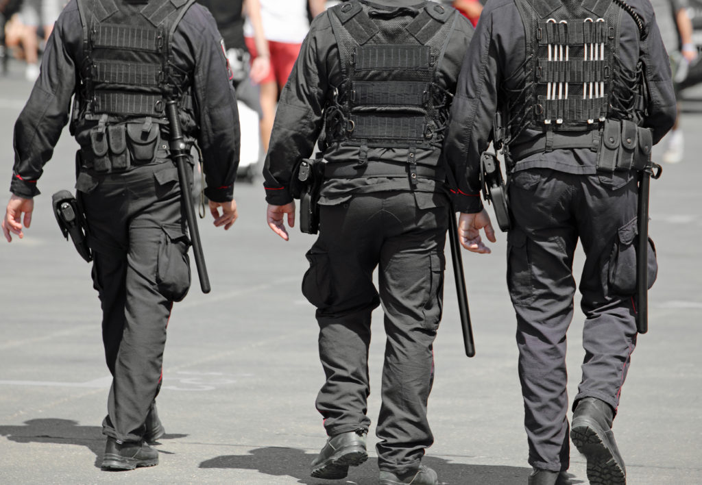 three policemen during the patrol of the city with riot uniform and batons