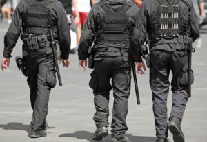 three policemen during the patrol of the city with riot uniform and batons