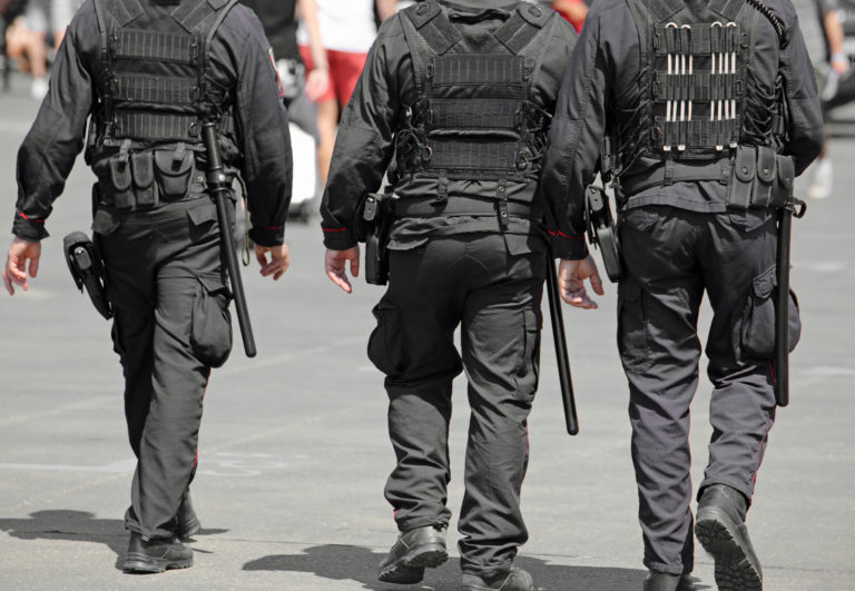 three policemen during the patrol of the city with riot uniform and batons
